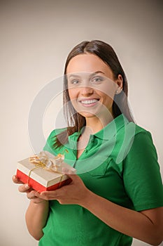 Young woman portrait hold gift in christmas color style . Smiling happy girl onn a light grey background