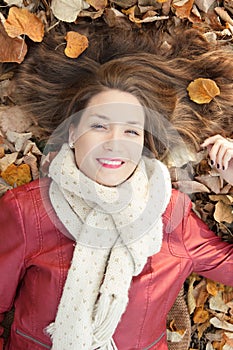 Young woman portrait lying on leaves, top view