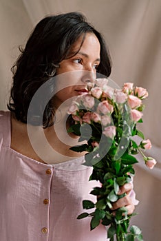 Young woman portrait with pink roses bouquet and natural light vertical close up. concept of midlife sophisticated woman.