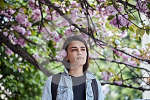 Young woman posing on the background of blooming sakura