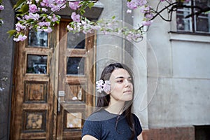 Young woman posing on the background of the old wooden door and blooming sakura