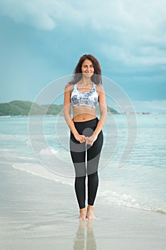 Young woman posing on the beach in sportswear. Female model on the sea shore.