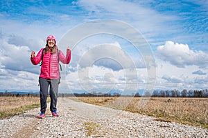 Young woman posing on dirt road surrounded with fields.