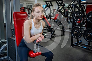 Young woman posing with dumbbells in her hands and works out in the gym performing an exercise