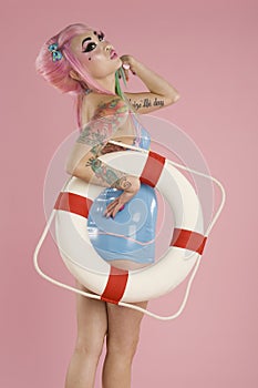 Young woman posing with float tube over pink background