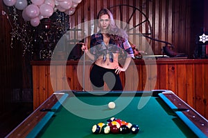 Young woman posing in front of billiard pool table