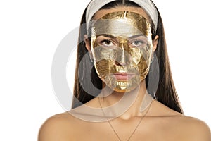 Young woman posing with golden mask on her face