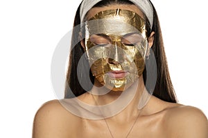 Young woman posing with golden mask on her face