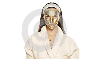 Young woman posing with golden mask on her face