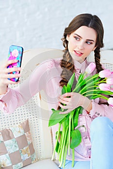 Young woman posing on her phone camera with flowers