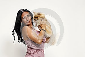 Young woman is posing with her Pomeranian dog in studio. Pets and animals concept.