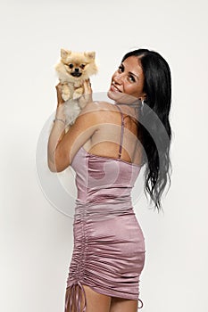 Young woman is posing with her Pomeranian dog in studio. Pets and animals concept.