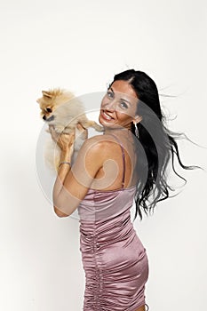 Young woman is posing with her Pomeranian dog in studio. Pets and animals concept.