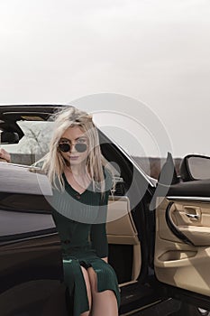 Young woman posing leaning on convertible car