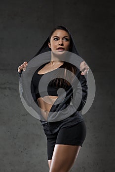 Young woman posing and showing muscles in gym