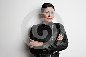Young woman posing in the studio wearing biker jacket with crossed hands.