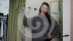 Young woman posing in sweater in fitting room store.