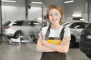 Young woman posing with wrenches in autoservice.