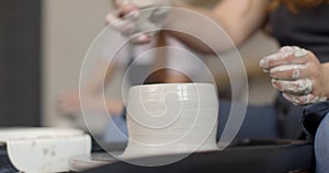 Young woman in pottery studio using pottery wheel, handmade ceramics, creative. Close-up of hands, slow motion