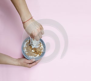 A young woman is pouring cereals with milk. Healthy breakfast.