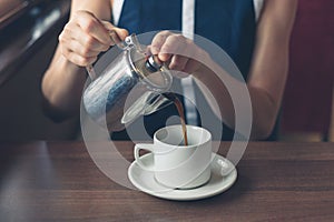 Young woman pouring coffee in diner