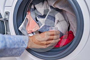 Young woman pouring detergent on washing machine at laundry room