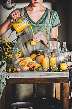 Young woman pouring fruit immune boosting drink to bottle