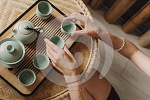 Young woman is pouring hot tea a tea ceremony. Woman hands holding cups. Wooden table with traditional Chinese tea ceremony