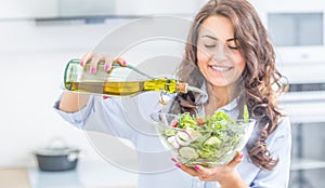 Young woman pouring olive oil in to the salad. Healthy lifestyle eating concept