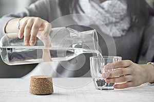 Young woman pouring water from bottle to glass