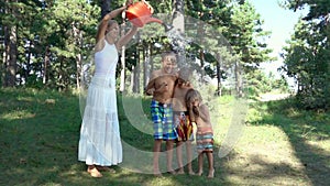 Young woman pouring water from a watering can on happy boys
