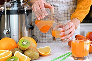 Young woman pours freshly fresh fruit juice into a glass. Making healthy fruit juices at home. Close-up. Selective focus