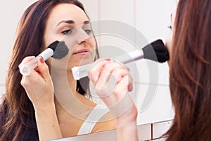 Young woman powdering in bathroom