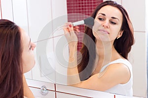 Young woman powdering in bathroom