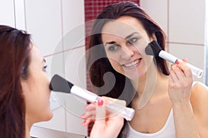 Young woman powdering in bathroom