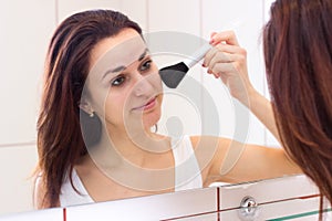 Young woman powdering in bathroom