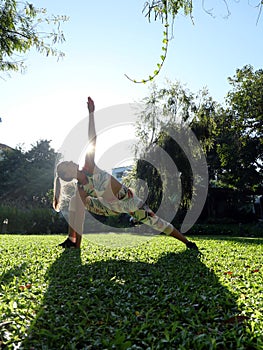 Young woman practice extended sides angle yoga pose at green grass outside. Vertical photo