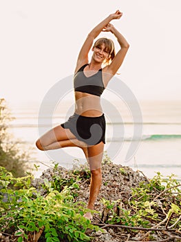 Young woman practice yoga at beach with sunset