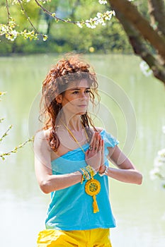 Young woman practice yoga outdoor by the lake hands in yoga mudra namaste gesture healthy lifestyle concept