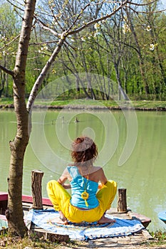 Young woman practice yoga outdoor by the lake healthy lifestyle concept back view