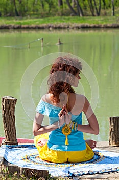 Young woman practice yoga outdoor by the lake healthy lifestyle concept back view full body shot