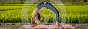 Young woman practice yoga outdoor in rice fields in the morning during wellness retreat in Bali BANNER, LONG FORMAT