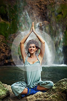 Young woman practice yoga outdoor on the rocks by the waterfall