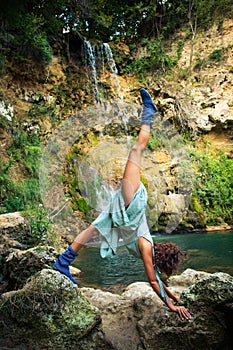 Young woman practice yoga outdoor on the rocks by the waterfall