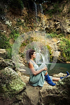 Young woman practice yoga outdoor on the rocks by the waterfall