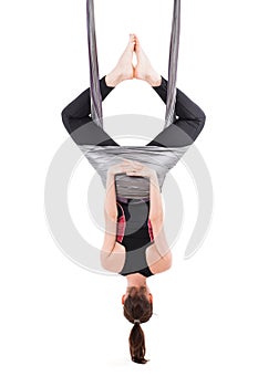 Young woman practices aerial anti-gravity yoga with a hammock