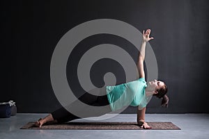 Young woman practices yoga asana Vasishthasana or side plank pose