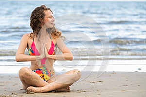 Young woman practices yoga on the beach in summer.