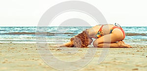 Young woman practices yoga on the beach in summer.