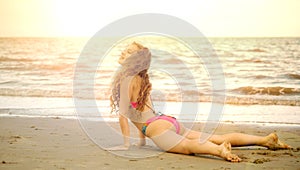 Young woman practices yoga on the beach in summer.